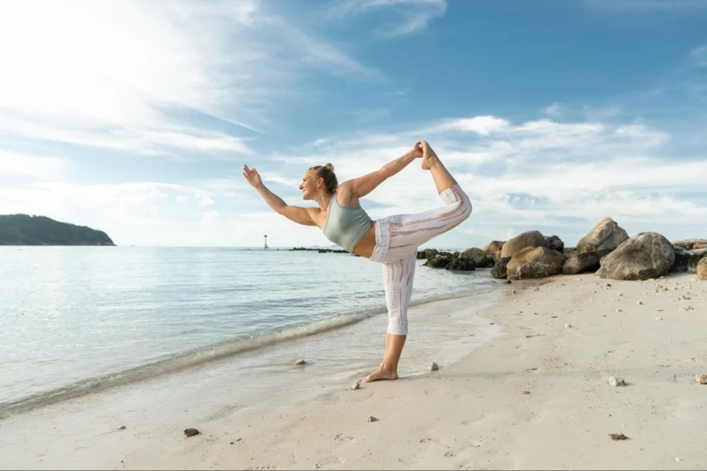 Woman practicing Dancer Pose on the beach during House of Om yoga teacher training in Koh Phangan