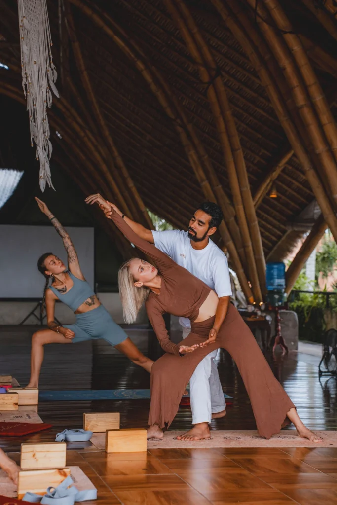 Yoga instructor demonstrating alignment and assisting a student during teacher training in Bali