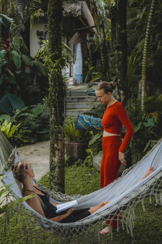 Yoga teacher training student carrying a yoga mat through the tropical grounds of The Mansion in Bali
