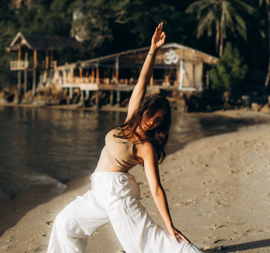 Woman practicing yoga on the beach during a House of Om training experience in Thailand