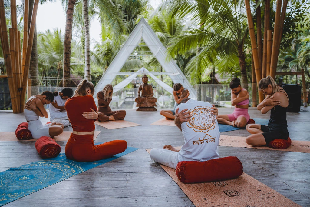 Yoga teacher training students practicing a seated self-awareness exercise in a bamboo shala