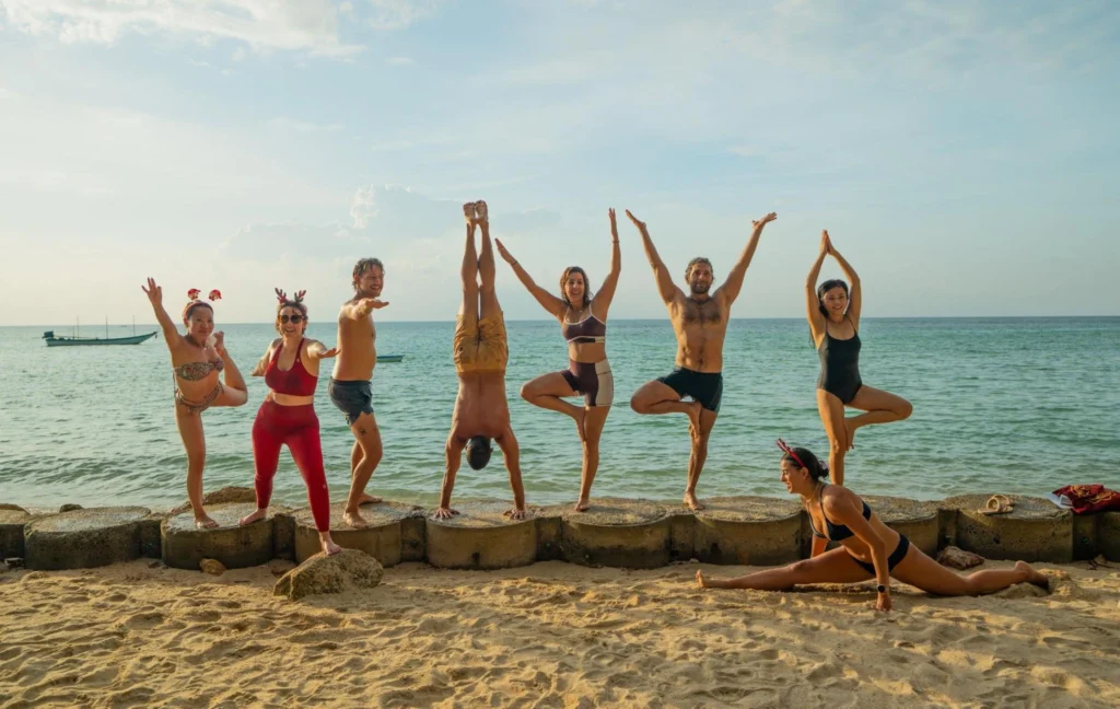 Yoga teacher training students practicing yoga together on a tropical beach in Thailand