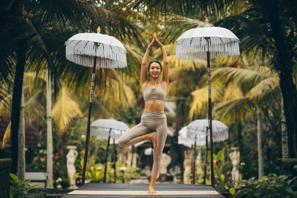 Woman practicing tree pose in a tropical garden during yoga teacher training in Ubud, Bali