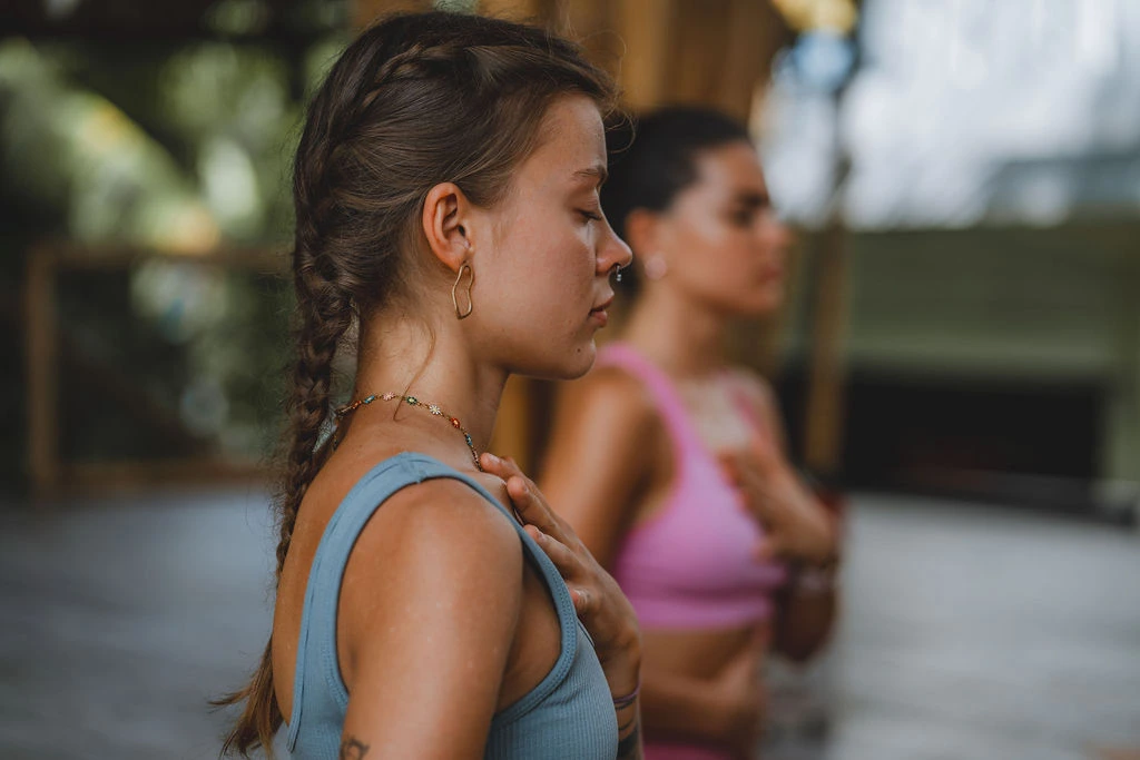 Yoga student practicing mindful breathing with a hand over her heart during Hatha yoga training