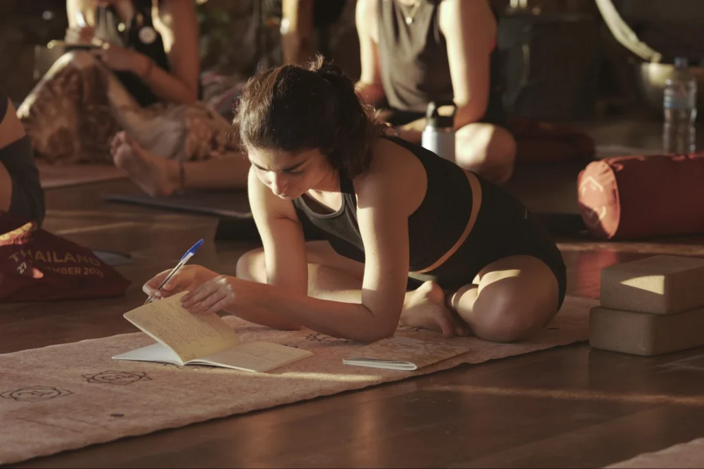 Student writing notes during a 200-hour yoga teacher training class in Thailand