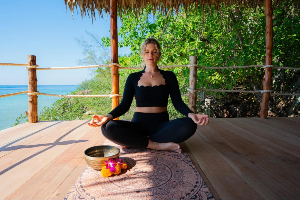 Woman practicing seated meditation beside the sea during yoga teacher training in Thailand