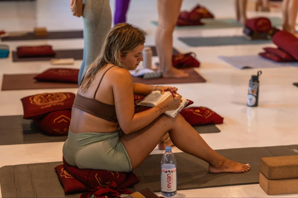 Student taking notes during a House of Om yoga teacher training class