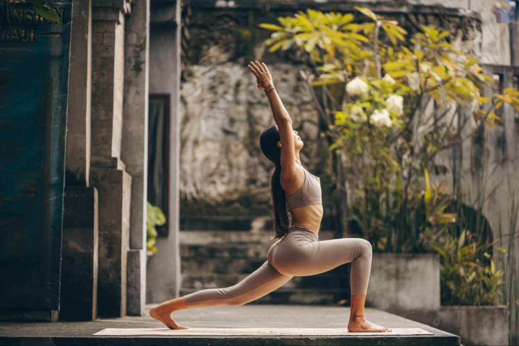 Woman practicing a high lunge yoga pose outdoors during a 200-hour yoga teacher training in Bali