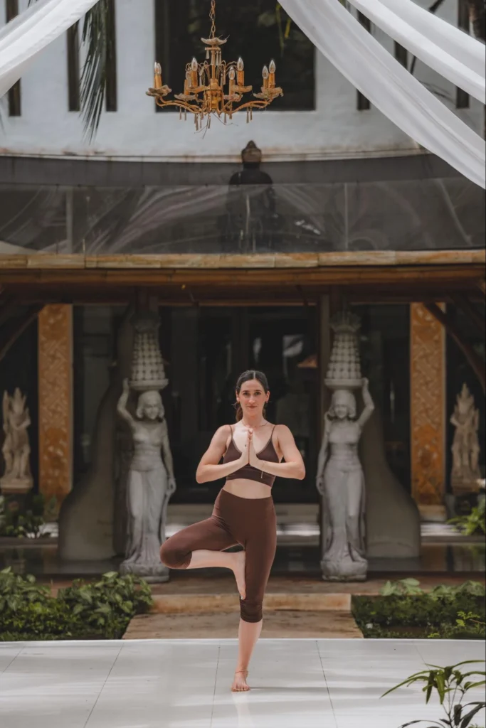 Yoga student practicing tree pose in a peaceful tropical setting in Bali