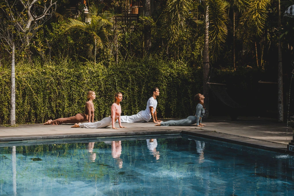 Yoga students practicing upward-facing dog beside the swimming pool at Amertham