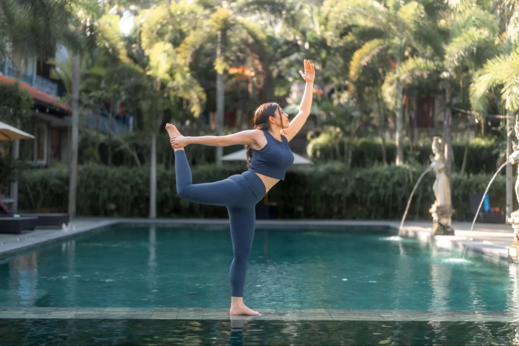 Yoga student practicing dancer pose beside the pool at Amertham in Bali