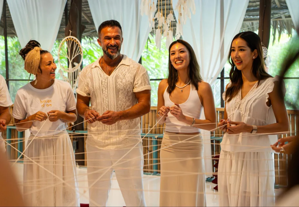 Yoga teacher training graduates celebrating with certificates on a tropical beach