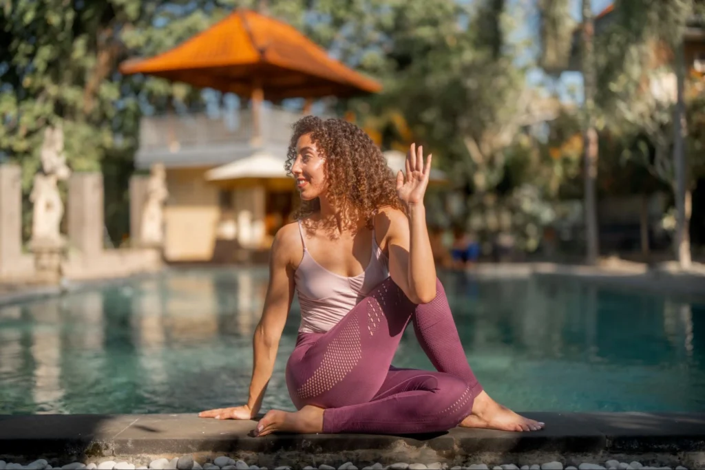 Yoga student practicing seated spinal twist beside the pool at Amertham Bali