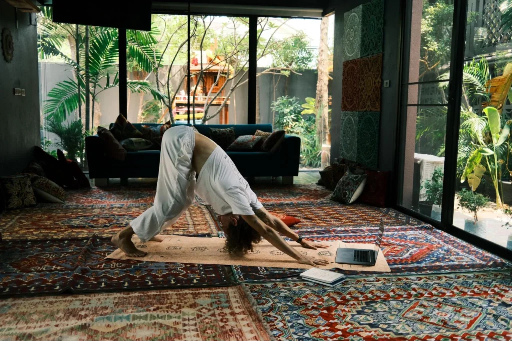 Student practicing yoga at home while following an online teacher training class