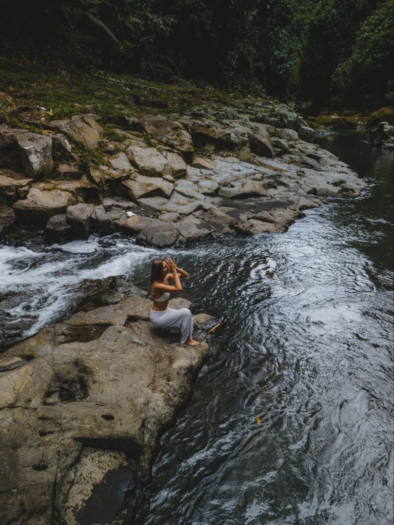 Yoga student meditating beside a jungle river during yoga teacher training in Bali