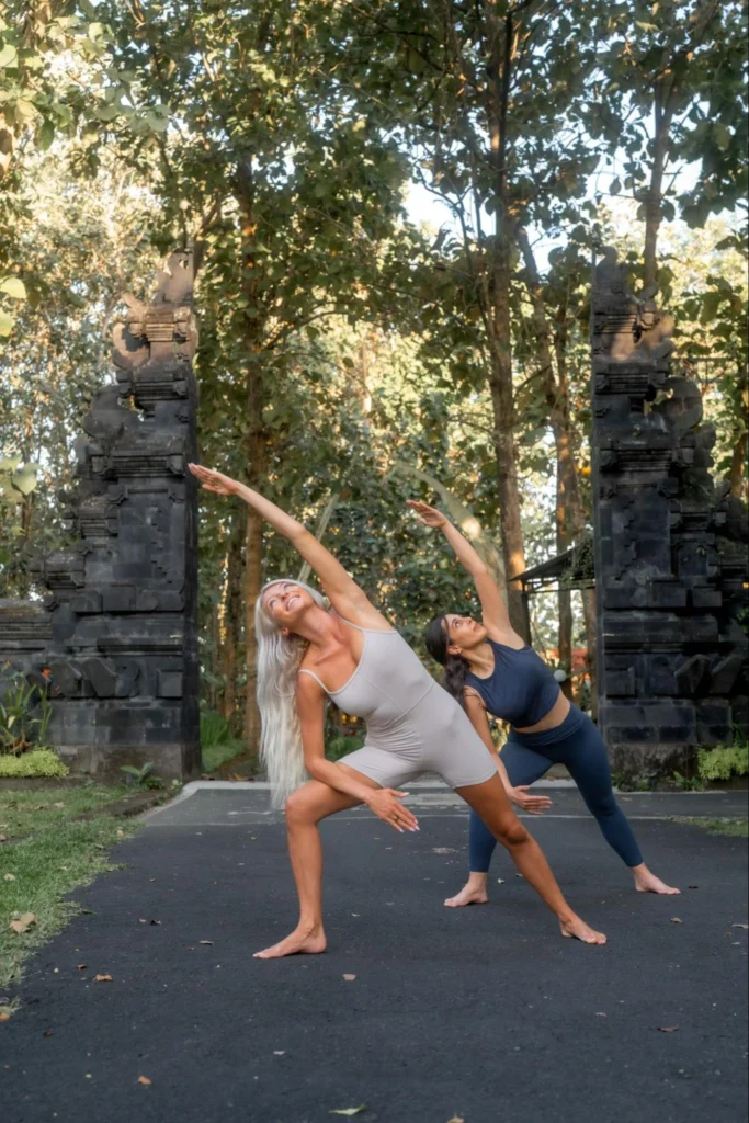 Two yoga students practicing side stretch outdoors at Amertham Bali