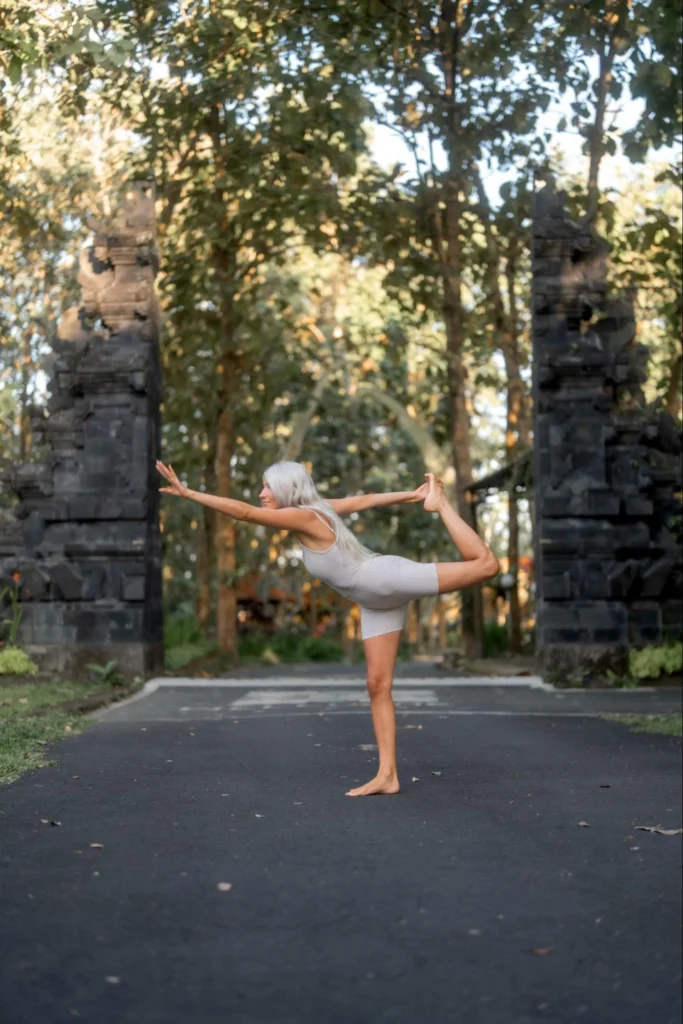 Yoga student practicing dancer pose between traditional Balinese gates at Amertham