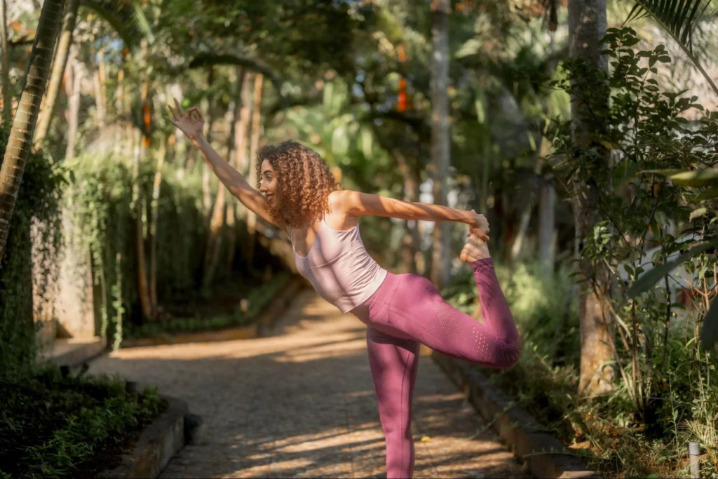 Yoga student practicing dancer pose outdoors in a tropical Bali setting