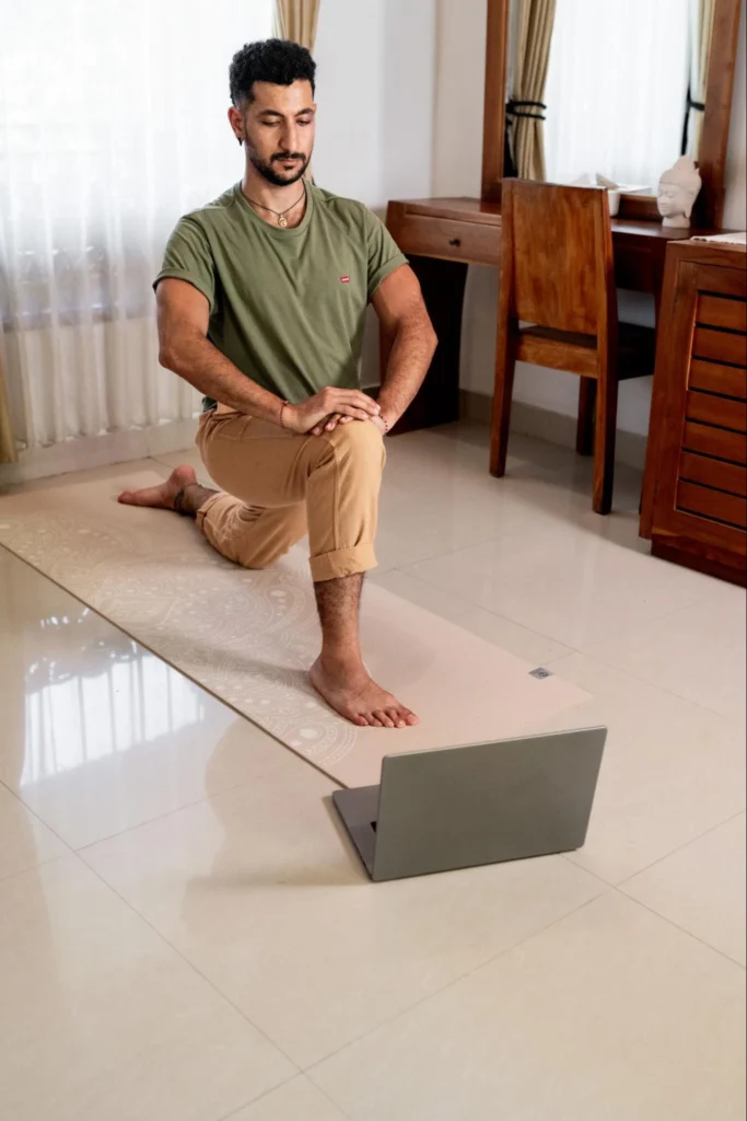 Yoga student practicing with a laptop during self-paced online teacher training