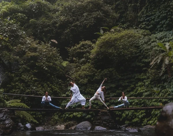 Students practicing yoga together in a tropical forest setting in Bali