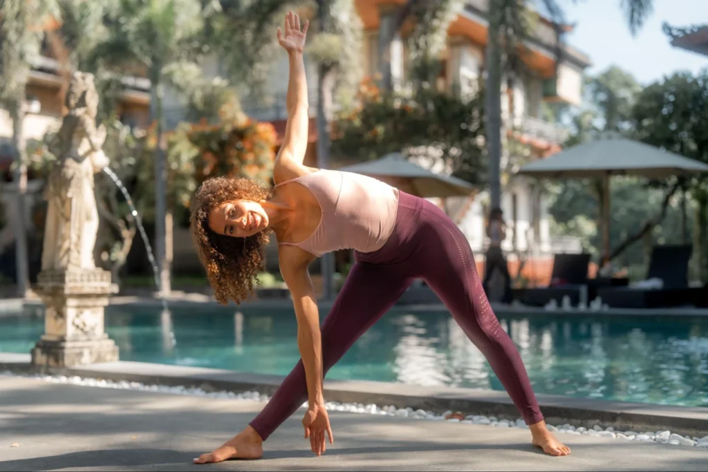 Yoga student practicing Triangle Pose beside the pool at Amertham Bali